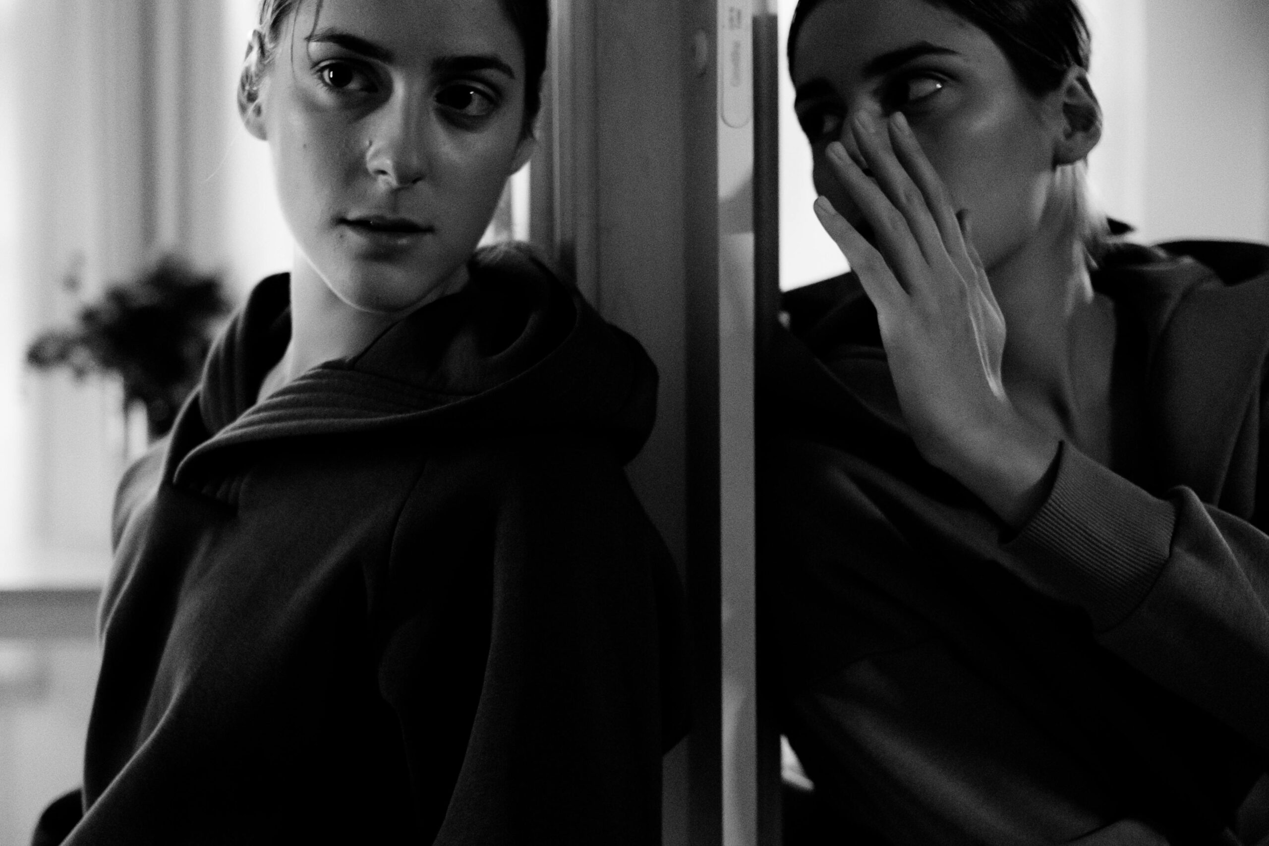 Black and white portrait of a woman in deep thought, whispering to her reflection.