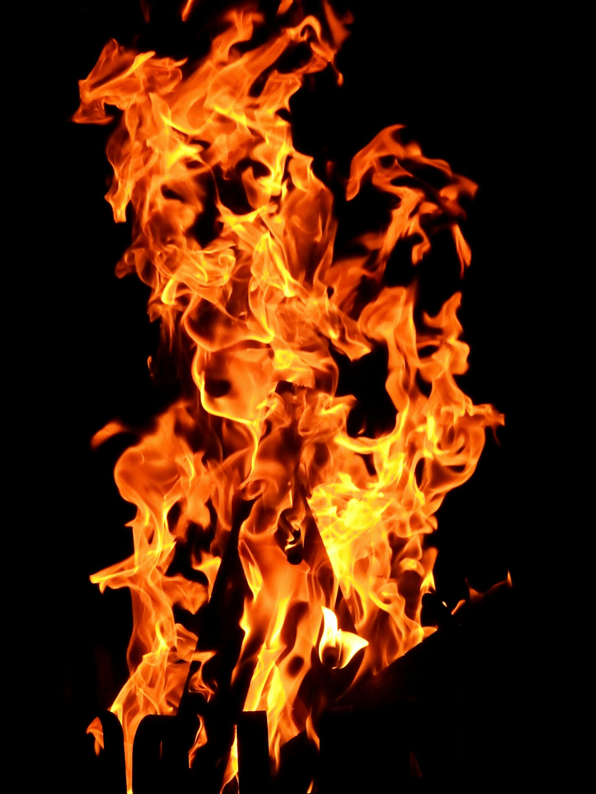Close-up fiery blaze with vibrant orange flames creating a dynamic pattern against a dark backdrop.